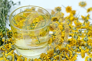 Herbal chamomile tea in a transparent glass.