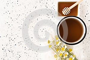 Herbal chamomile tea in white cup and honey on white cement background