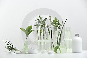 Herbal cosmetic products, laboratory glassware and ingredients on white table