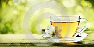 Herbal cup of tea on wooden table over nature green bokeh background with space. Hot chinese beverage in mug design banner. Tea