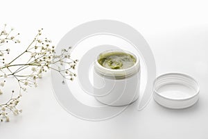 Herbal dermatology cosmetic hygiene green cream with flowers. skincare product in container on white background. Skincare cosmetic