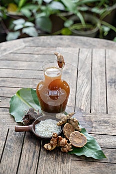 Herbal drinks of beras kencur are packed in glass bottles serving with raw materials