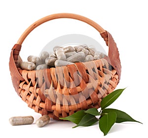Herbal drug capsules in wicker basket. Alternative medicine concept.
