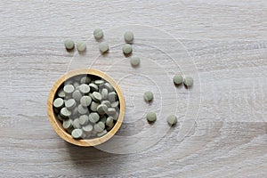 Herbal extract medicine tablets pills or Fa thalai chon Andrographis Paniculata, Acanthaceae in wooden bowl on wooden background