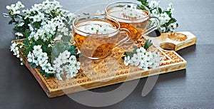 Herbal flower tea from haw thorn blossom on wooden cutting board on black background