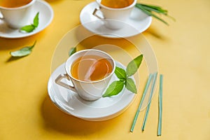 Herbal green tea with lemongrass in glass cup with fresh limes. Top view of three white cups of Lemon Grass Drink on a Yellow