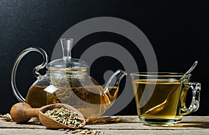 Herbal infusion fennel tea in glass cup with dried fennel seeds in wooden shovel