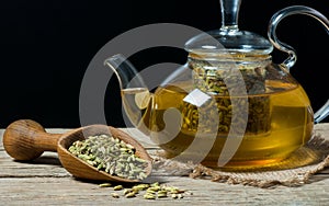 Herbal infusion fennel tea in glass cup with dried fennel seeds in wooden shovel