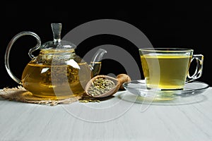 Herbal infusion fennel tea in glass cup with dried fennel seeds in wooden shovel