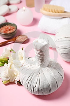 Herbal massage bags and other spa products on pink background, closeup