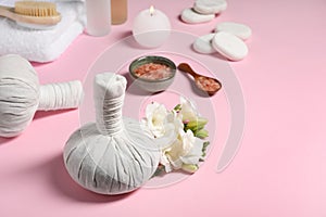 Herbal massage bags and other spa products on pink background, space for text