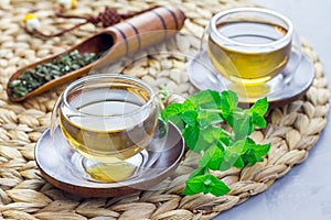 Herbal mint tea in oriental glass cup with fresh peppermint and tea scoop on background, horizontal