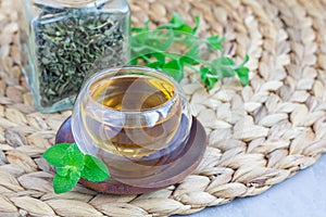 Herbal mint tea in oriental glass cup with fresh peppermint and tea scoop on background, horizontal, copy space