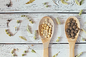 Herbal pills and dry herbs on wooden background.