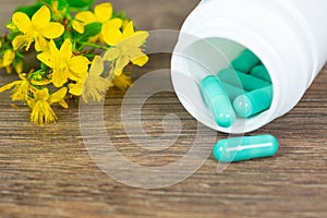 herbal pills with open plastic bottle and herb flowers