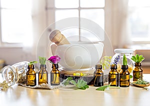 Herbal remedy composition concept. Essential oil bottles with mortar and pestle and leaves. photo