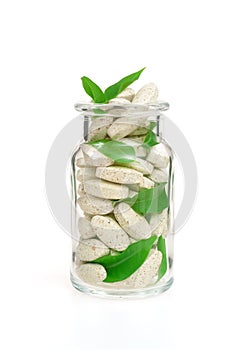 Herbal supplement pills and fresh leaves in glass photo