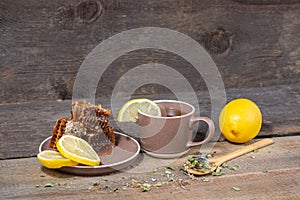 Herbal tea in a ceramic mug, honey in a plate and lemon on a wooden table. Still life