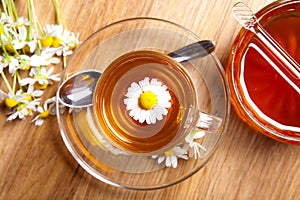 Herbal tea of chamomile, with blossoms, honey, on rustic wooden flooring