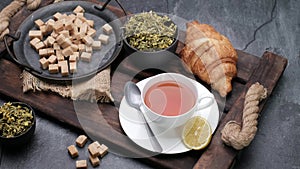 Herbal tea, croissant and white sugar. Close-up video shooting, dark background