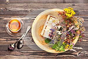 Herbal tea cup, healing herbs and honey in a wooden bowl on a wooden table