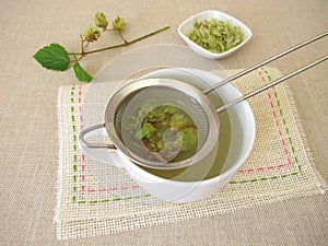 Tea with dried hop flowers in tea strainer