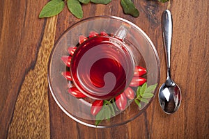 Herbal tea with fresh rose hip on wooden background