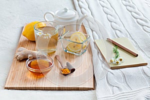 Herbal tea in glass cup with flowers of chamomile, turmeric and honey on a wooden board.