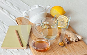 Herbal tea in glass cup with flowers of chamomile, turmeric and honey on a wooden board.