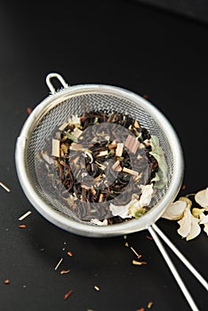 Herbal Acaccia Tea Healthy Drink in bowl and sieve over Black Background copy space. Healthy Drink, coldness.