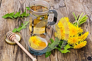 Herbal tea and honey from dandelions on wooden background.