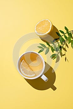 Herbal tea with lemon in a white cup on a yellow background. Detox drink concept for immunity