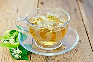 Herbal tea of linden flowers in glass cup on board