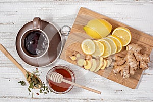 Herbal tea in a mug, lemon, honey and ginger cut into pieces top view