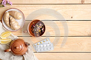 Herbal tea, pills, teapot, lemon and ginger root on wooden table, alternative medicine concept, flat lay style composition, view