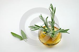 Herbal tea with rosemary and two leaves of sage laiyng near glass