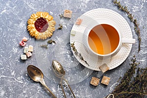 Herbal tea with thyme with sweets on a gray background, top view. Flat lay