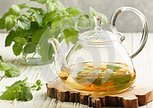 Herbal tea in a transparent teapot on the table and sprigs of fresh Melissa lemon balm and mint