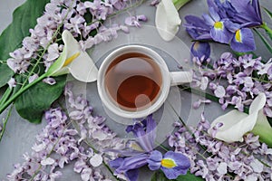 Herbal tea with wisteria, irises, white callas on gray background.