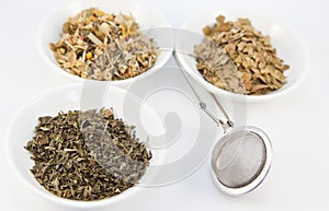 Herbal teas in small white bowls with infuser