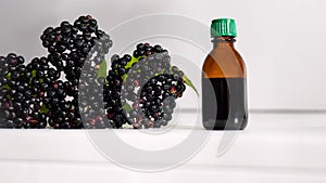 Herbal tincture of black berries, medicinal elderberry on a white background.