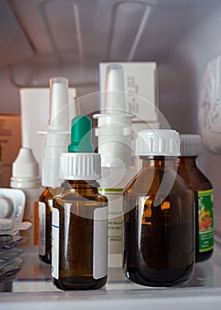 Herbal tincture vials, nosal sprays, eye drops and boxes on the refrigerator shelf close-up.