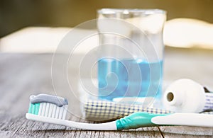 Toothbrush with toothpaste and mouthwash on wooden table.