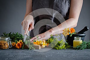 Herbalist woman chopping medicinal herbs with a knife to prepare healing medicines for treatment.