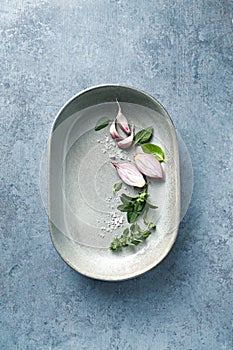 Herbs, challots and garlic cloves in a ceramic dish