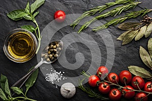 Herbs mix with tomatoes and olive oil on the black stone table