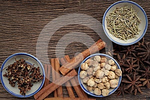 Herbs and spices for cooking in bowls on a wooden background.