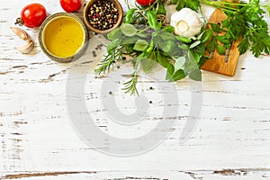 Herbs spices, olive oil and vegetables on a wooden table. Top view flat lay background. Copy space