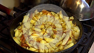 Herbs sprinkled potatoes, which is cooked in a cast iron pan on a gas stove