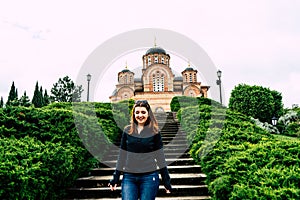 Hercegovacka Gracanica - Orthodox church in Trebinje, Bosnia and Herzegovina. Red head Girl smiling going down the stairs